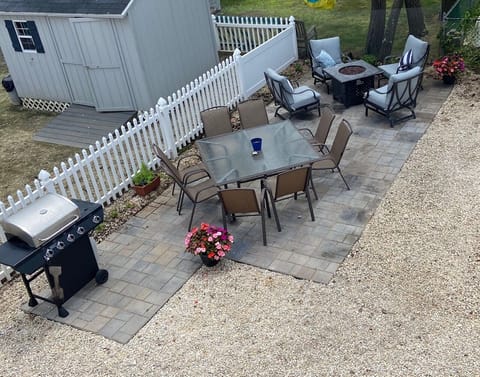 Backyard patio showing gas BBQ grill, seating area and firepit
