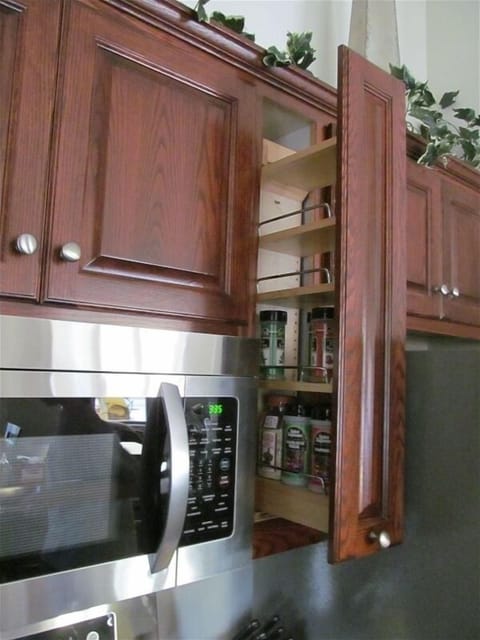 a spice rack and lazy susans are some of the cabinet features in the kitchen