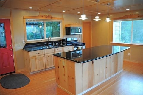The upstairs kitchen with knotty pine and huge black granite island countertop.