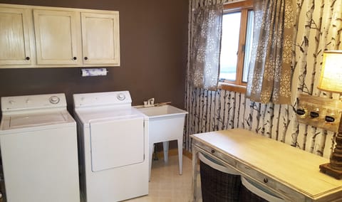 Fully equipped laundry room with utility sink and table for folding.