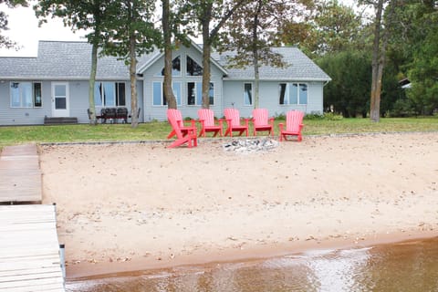 Looking at the home from dock.  Adirondack chairs around firepit on the beach.