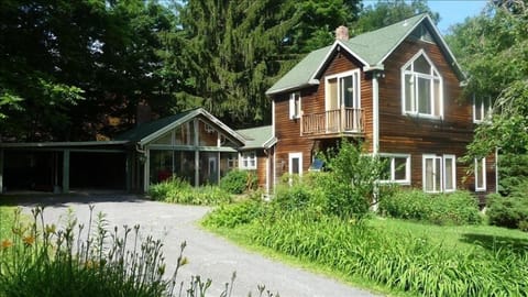 Serenity- springtime view of house:gardens, balcony, two bay garage, sun porch.