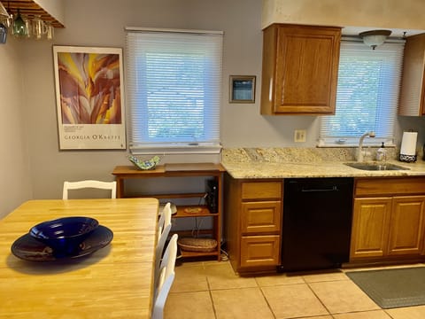 Kitchen w granite counters and equipped with china and wine glasses.