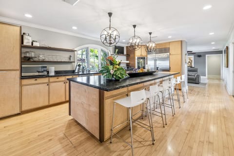 Chef’s kitchen with bar seating, stainless steel appliances, and easy access outdoors.