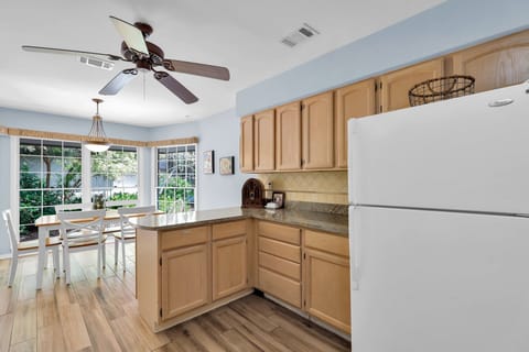 The kitchen is equipped with an oven, fridge, dishwasher, and microwave, and two bar stools at the breakfast bar.