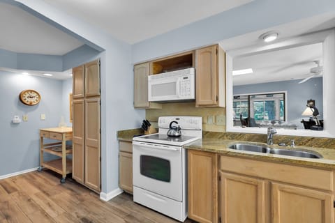 The kitchen is equipped with an oven, fridge, dishwasher, and microwave, and two bar stools at the breakfast bar.