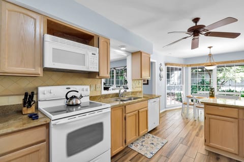 The kitchen is equipped with an oven, fridge, dishwasher, and microwave, and two bar stools at the breakfast bar.