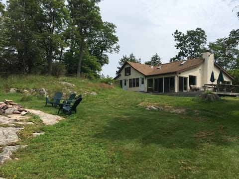 House with large outdoor deck, grill and lots of seating.
