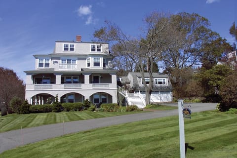 Front of SNI Cottage, showing various verandas, oceanview windows, lawn.