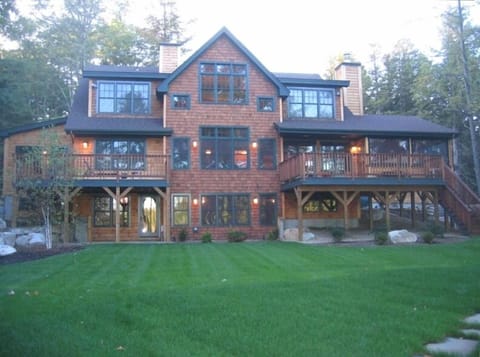 Lakeside view of house. Two decks. Large lawn.