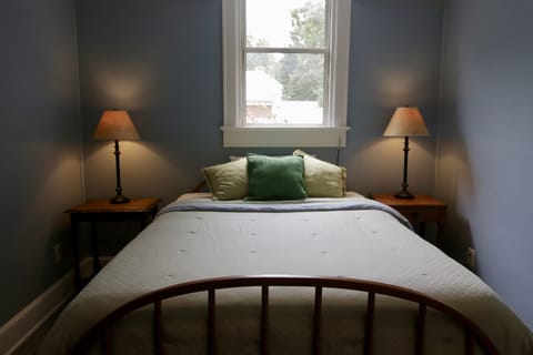 Queen bed in bedroom.  Bamboo blind to reduce morning light.