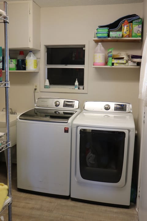 Utility room with a large capacity washer and dryer and laundry tub.