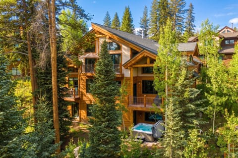 A stunning mountain retreat nestled among towering pines and aspens, featuring warm wood architecture, multi-level balconies, and a private hot tub surrounded by nature's serenity.
