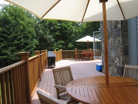 Deck with a grill, two tables, umbrellas and chairs with large seating capacity