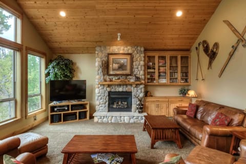 Warm living room w/ leather seating, stone fireplace & wood-beamed ceilings