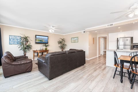 Vantage point from this upper unit's front French doors toward kitchen, living room and dining area. Ceiling fans and wood laminate flooring throughout main living areas.