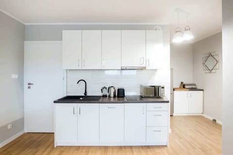 A clean, white kitchen with modern cabinetry, a sleek countertop, and essential appliances. The open layout makes it functional and easy to navigate.