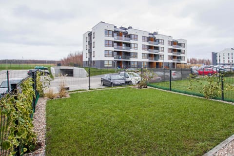 A outdoor green space with neatly trimmed grass and plants, situated between residential buildings.