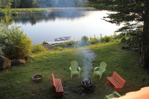 Lakefront private view from deck with boat, dock, fire pit, and swing. 