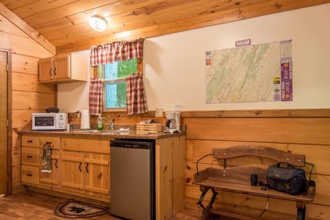 Standing in front of table facing kitchenette. Cabin entrance is on the right, bathroom door is just left of the kitchen counter.