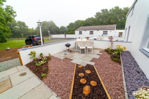 Gated front garden with lots of plant life and BBQ. 