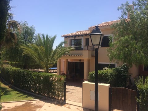 Rear of the villa with outdoor dining furniture and gate leading to the pool