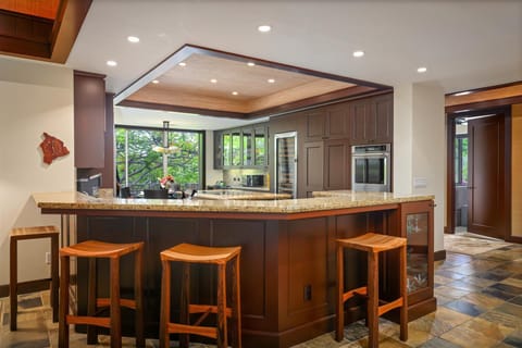 Gourmet kitchen with bar seating, open to lush views and fully equipped for chef-crafted meals or quick bites.