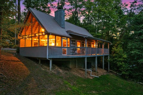 Charming Smoky Mountain cabin in Pigeon Forge with glowing windows, a covered porch, and wooded privacy — your perfect Tennessee getaway