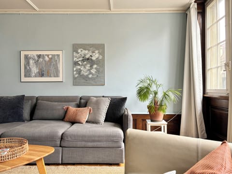 Large living room with lots of seating, natural light and a TV.