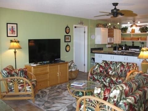 Open floor plan with 55-inch Smart TV and Hawaiian print upholstered furniture.
