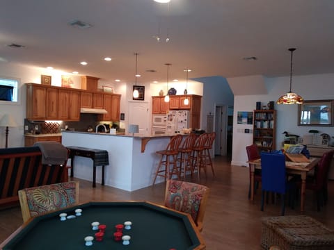 Great room with bumper pool, dining, living room and kitchen overlooking water.