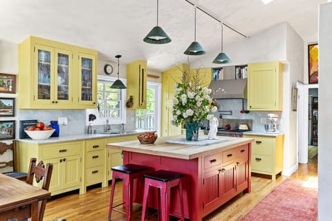 Bright and cheerful kitchen featuring sunny yellow cabinets and red island