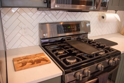 New 6 burner gas range. Under cabinet lights, black stainless steel appliances.