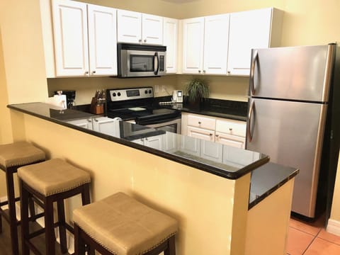View of kitchen - stainless steel appliances, granite counter tops, bar stools