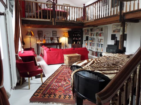 Main room with grand piano in foreground, bed upstairs on gallery