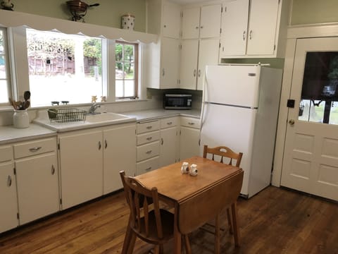 Kitchen with refrigerator, oven, microwave, toaster and small table.