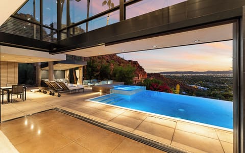 Glass walls open to a resort-style pool deck with desert views for sunset swims.