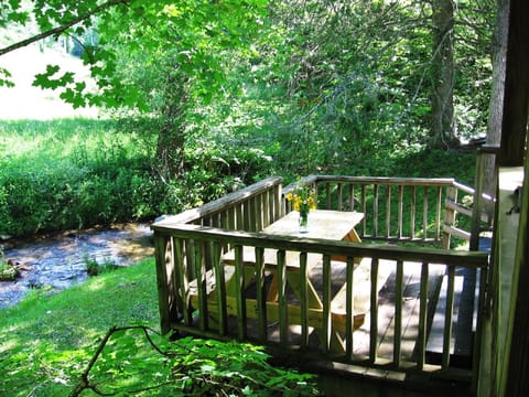 Picnic table off of covered porch overlooking the creek