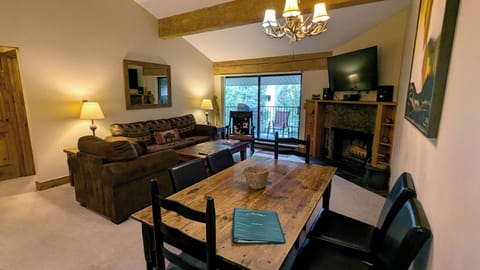 Living room with sofa bed, wood fireplace, dining table, and balcony w/ gas BBQ