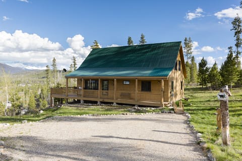 View of main entrance, parking area, and covered part of deck