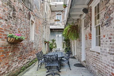 Features exposed brick walls, outdoor seating, and hanging plants.