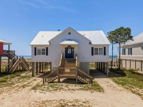 A charming beachfront cottage elevated on stilts with ocean views just beyond the dunes, offering easy access to the sand and surf.