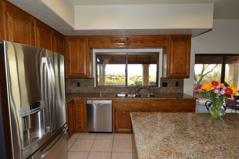 Kitchen has new stainless appliances and a view of city and kitchenette table.