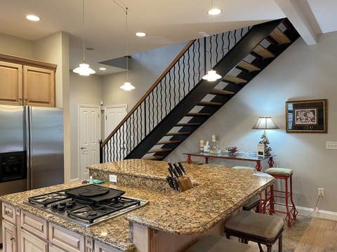 Large 2-tier island with 6 bar stools. Dacor gas stove in center & subzero wine