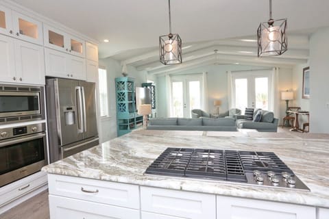 Open kitchen with marble counter tops and large island with gas cooktop