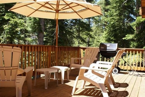 Deck in summer: Large sun umbrellas, gas BBQ grill, tables, chairs.