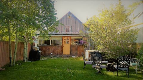 Large backyard equipped with firepit, loan chairs and grill.