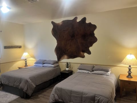 Spacious bedroom with two queen beds and a desk.