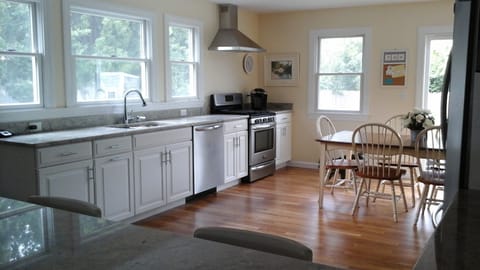 Newly remodeled kitchen with large dining table and stainless steel appliances.