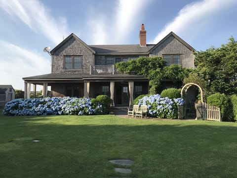Back porch surrounded by lush hydrangeas and large landscaped yard.